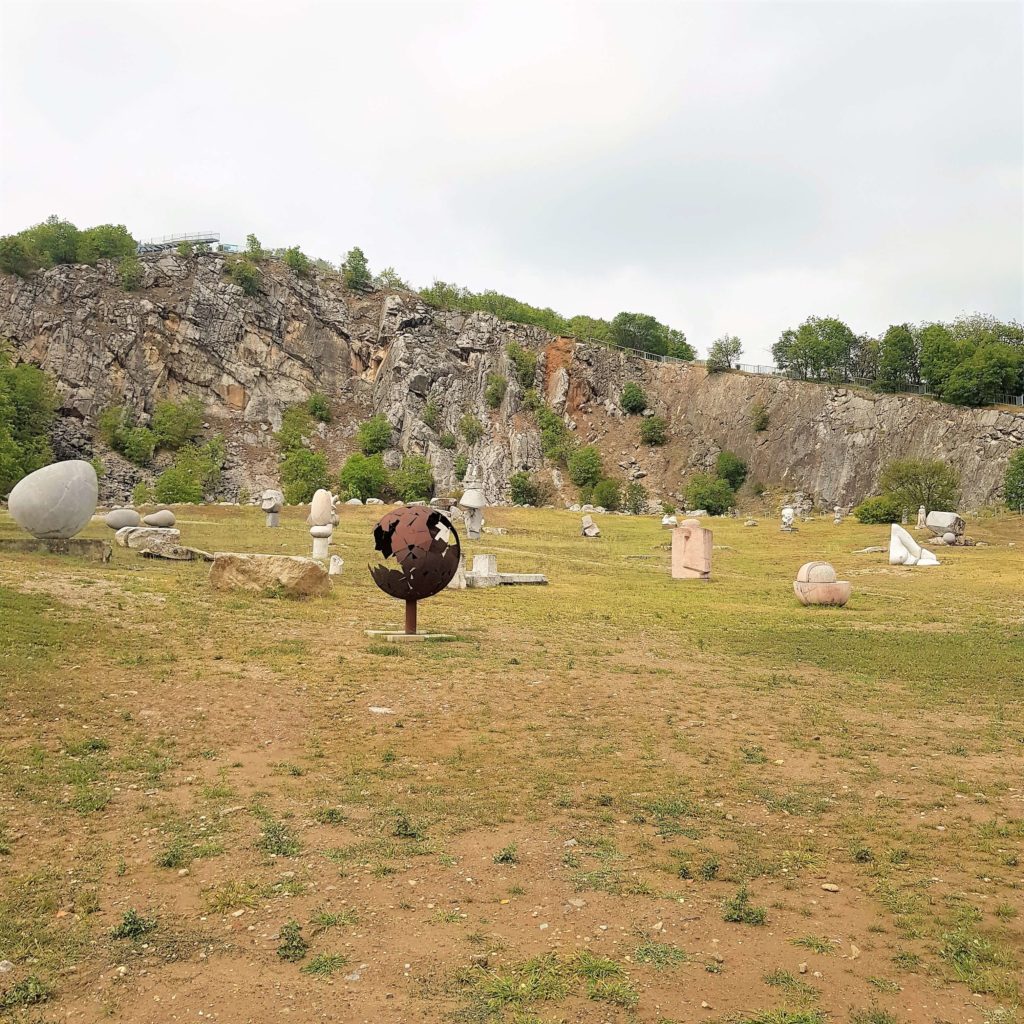 Stone statues against the backdrop of the towering walls of the quarry