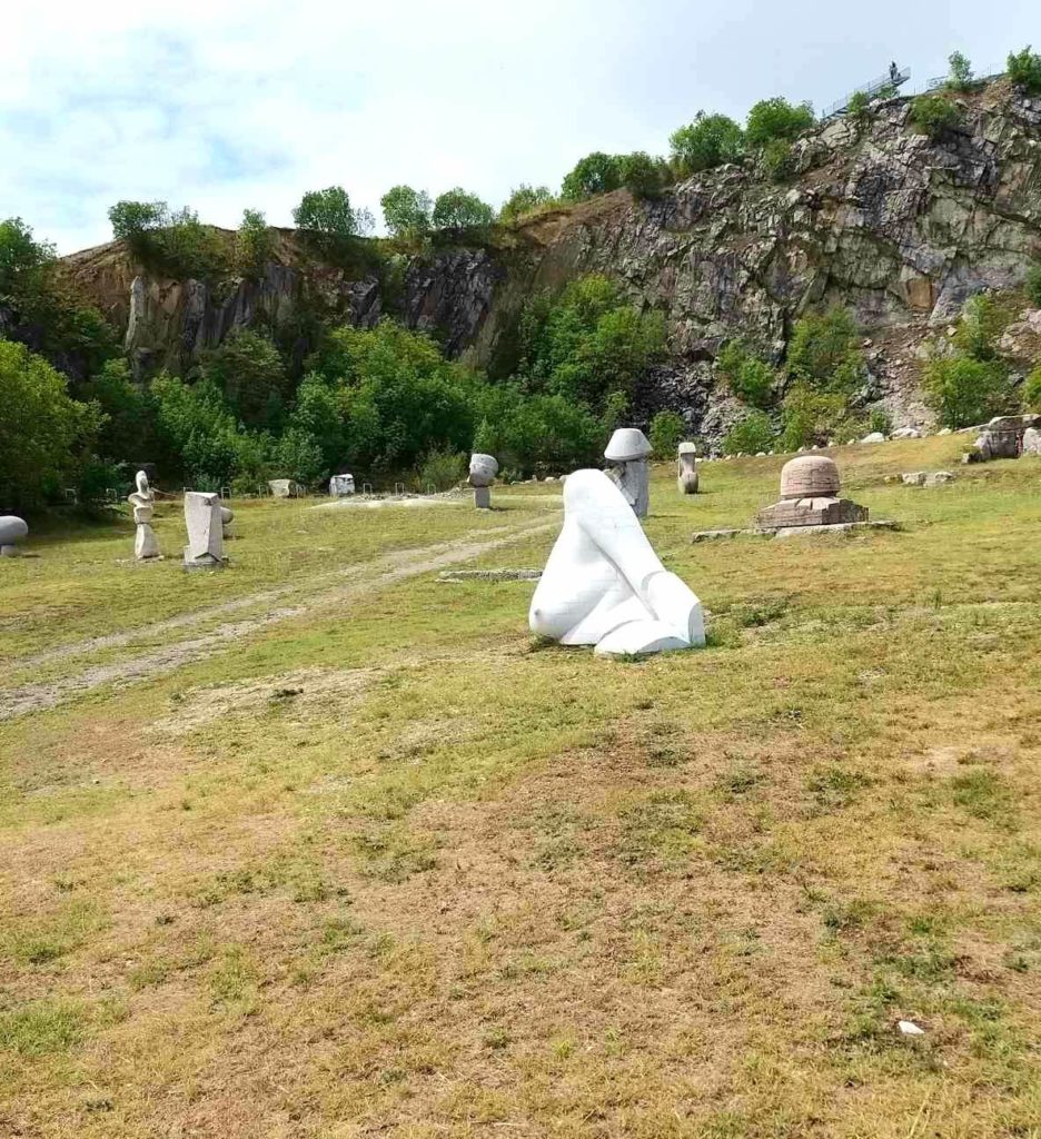 Stone statues in front of quarry's rock wall