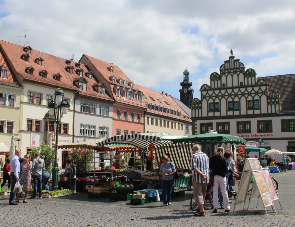 Weimar: locals shopping from the market stalls. In the background, the tourist information office