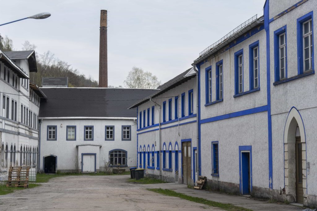 A courtyard view of the Schindlers Werk Blue Dye Factory with a high rising chimney